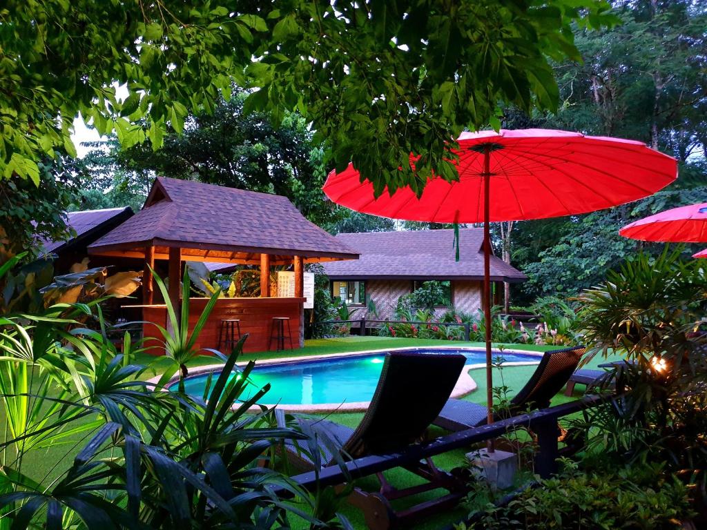 a pool with a gazebo and a red umbrella at Khao Sok Cabana Resort in Khao Sok
