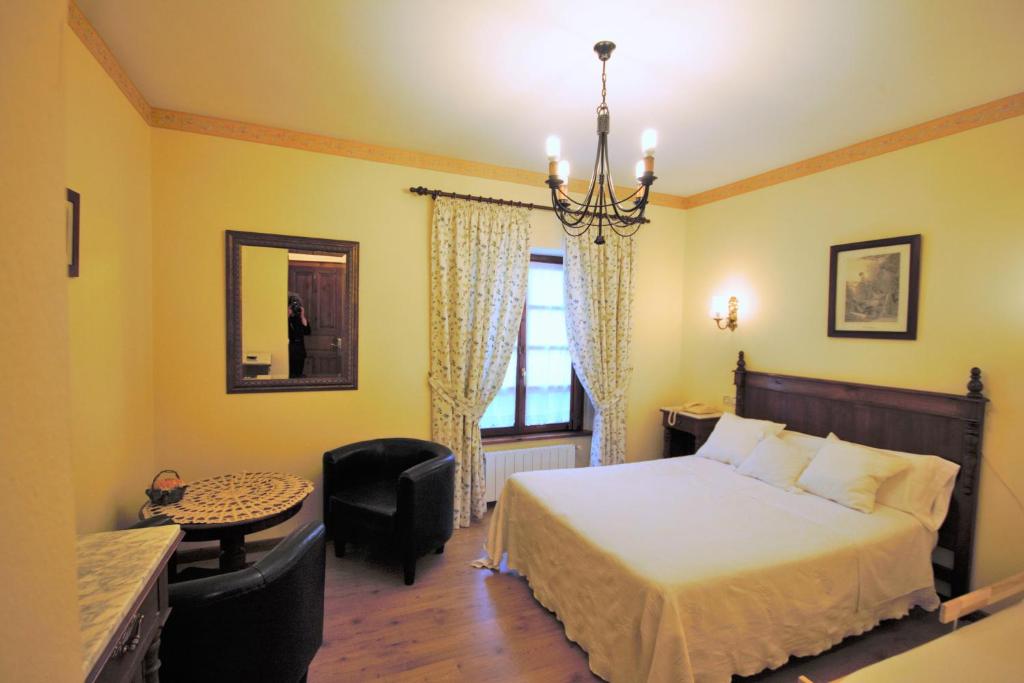 1 dormitorio con 1 cama, 1 silla y 1 ventana en Hotel Rural Ovio, en Nueva de Llanes