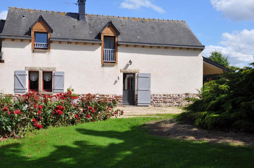 a large white house with flowers in the yard at Perrault Gites in Loscouët-sur-Meu