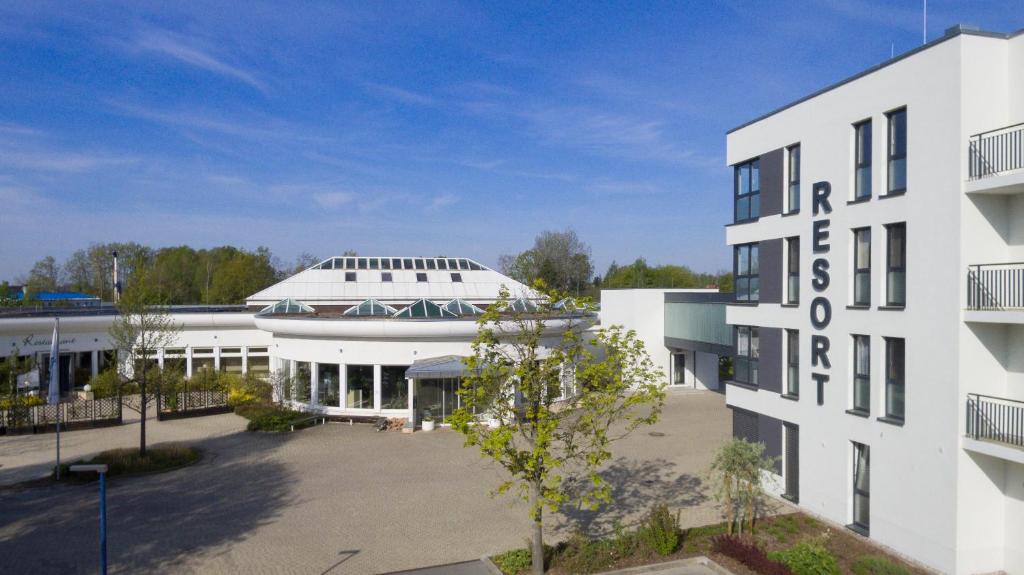 ein weißes Gebäude mit einem Parkplatz davor in der Unterkunft Riff Resort in Bad Lausick
