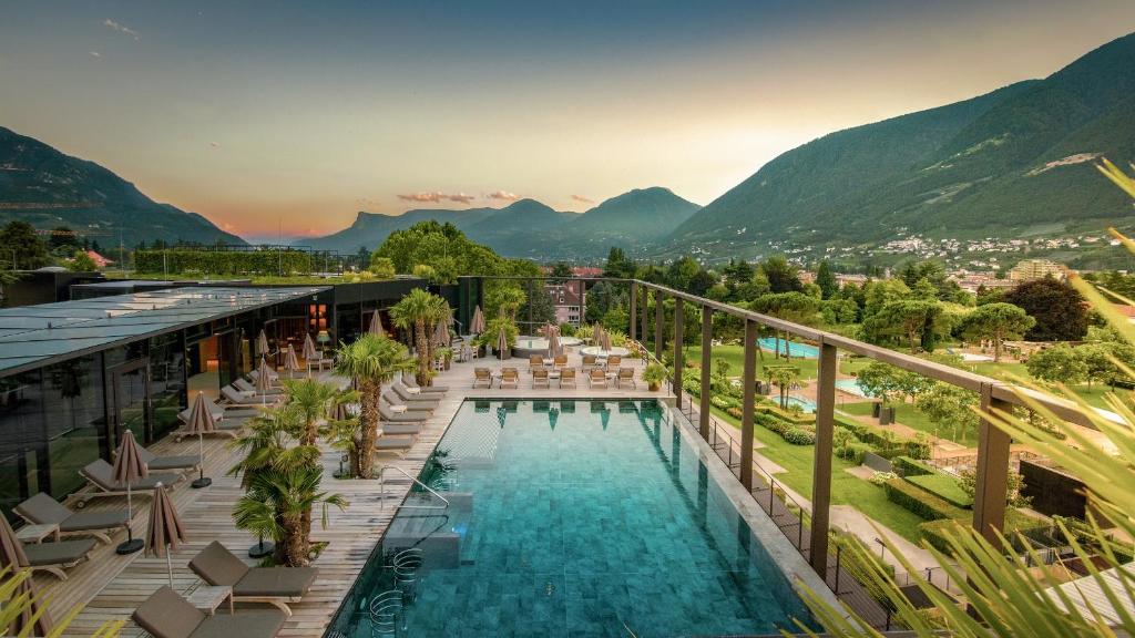 un hotel con piscina y montañas de fondo en Hotel Therme Meran - Terme Merano, en Merano