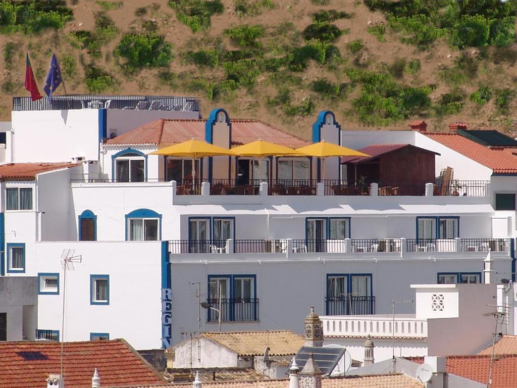 um edifício branco com guarda-chuvas amarelos em cima em Apartamentos Turisticos Regina em Albufeira