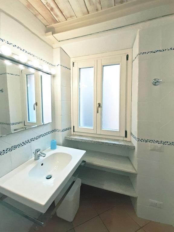 biała łazienka z umywalką i lustrem w obiekcie Appartamento elegante a Marina di Campo w mieście Campo nell'Elba