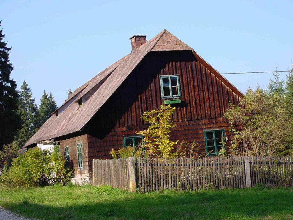 uma casa de madeira com uma cerca em frente em Ferienhaus Juster im Wald em Gutenbrunn