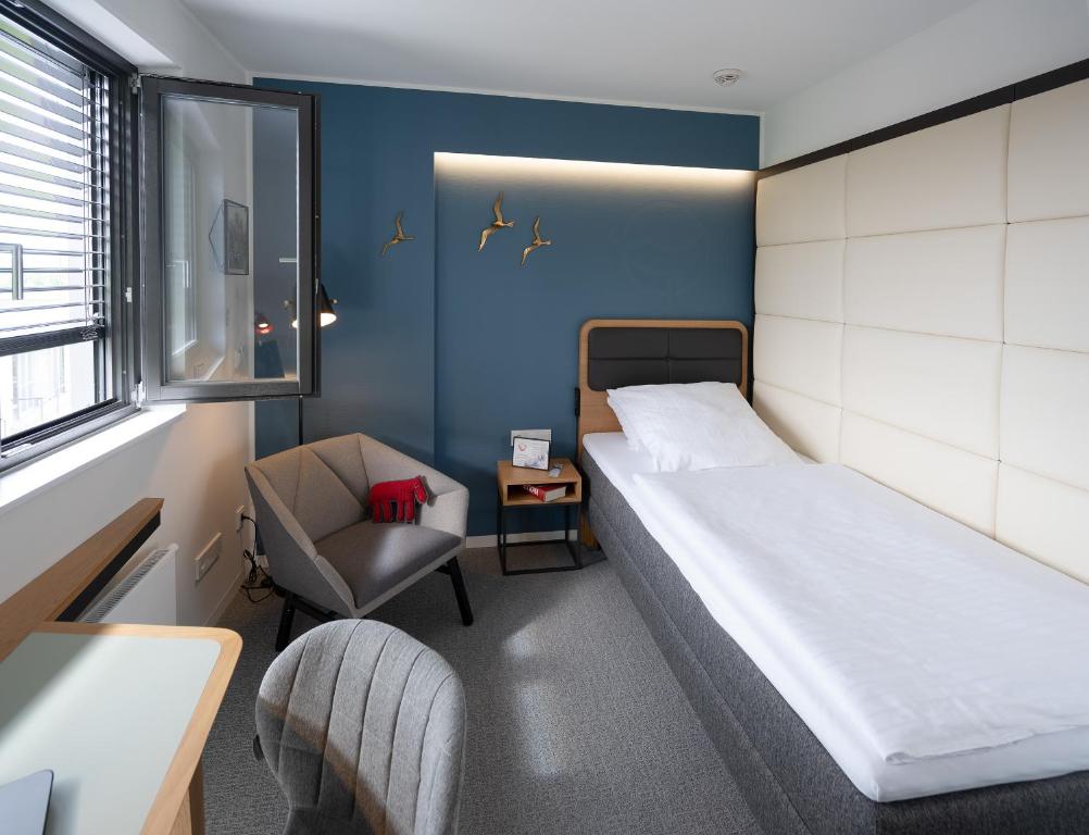 een kleine kamer met een bed en een stoel bij Hotel Am Leinritt in Kahl am Main