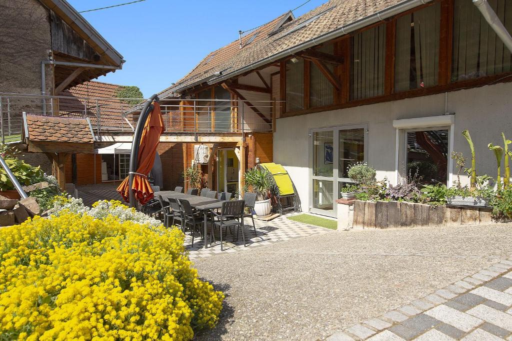 Le Domaine du Verger gîtes et SPA في Osenbach: منزل به طاولة وكراسي وزهور صفراء