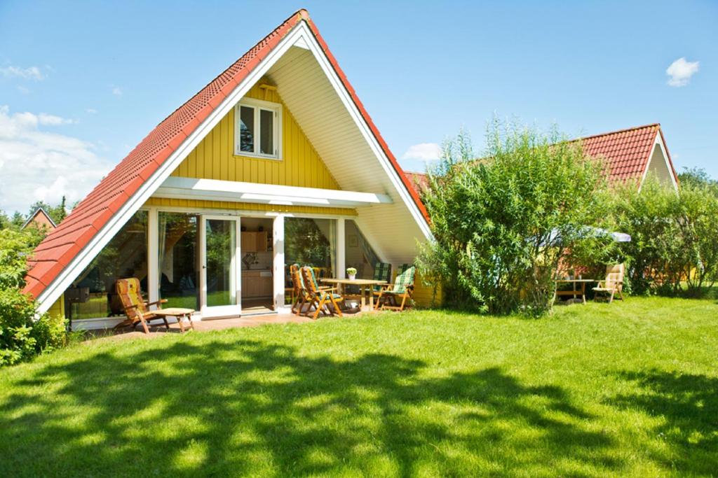 een geel huis met een tafel en stoelen in een tuin bij Ferienhof Ebsen in Langenhorn