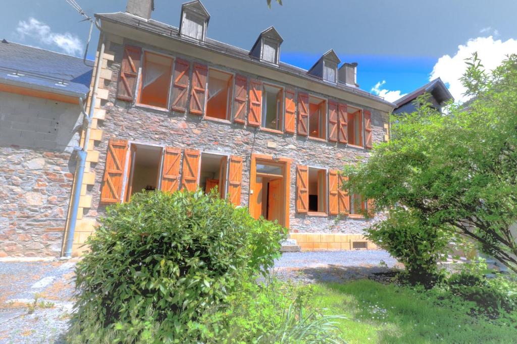una vecchia casa in pietra con porte e finestre arancioni di Maison Burgalat a Saint-Mamet