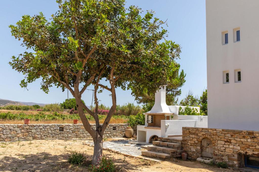 a tree in a yard next to a white building at Oneiric Harmony in Mikri Vigla