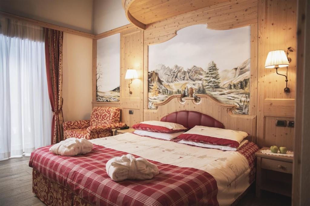 una camera con un letto con una coperta rossa e bianca di Hotel Rubino Deluxe a Campitello di Fassa