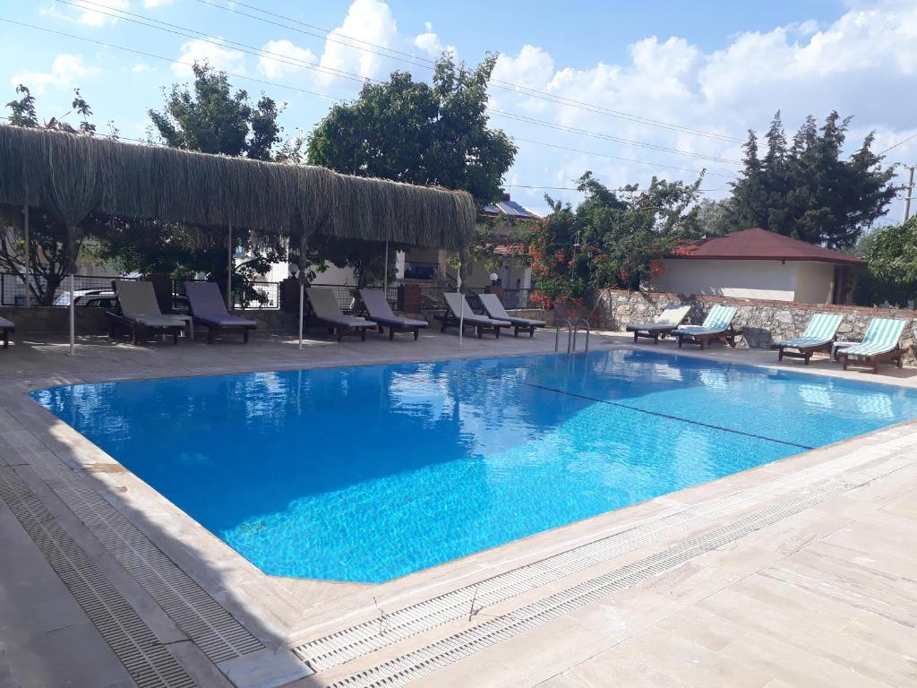 a large swimming pool with blue water and lounge chairs at Hotel NilSu in Oludeniz