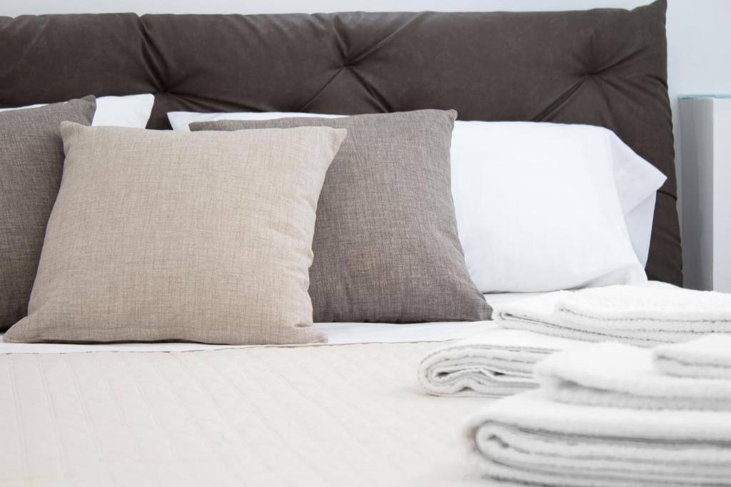 a bed with white pillows and towels on it at Cortile Osterio XIV in Cefalù