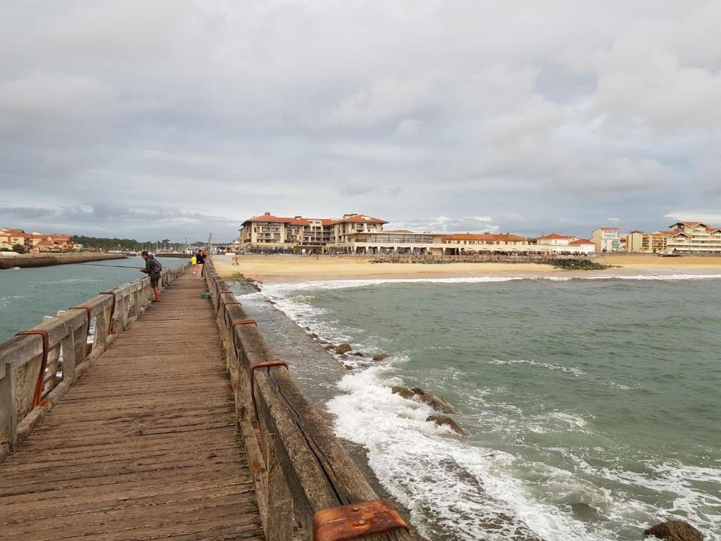 Un homme se promène sur une jetée en bois à côté de la plage. dans l'établissement magnifique appartement Capbreton, à Capbreton