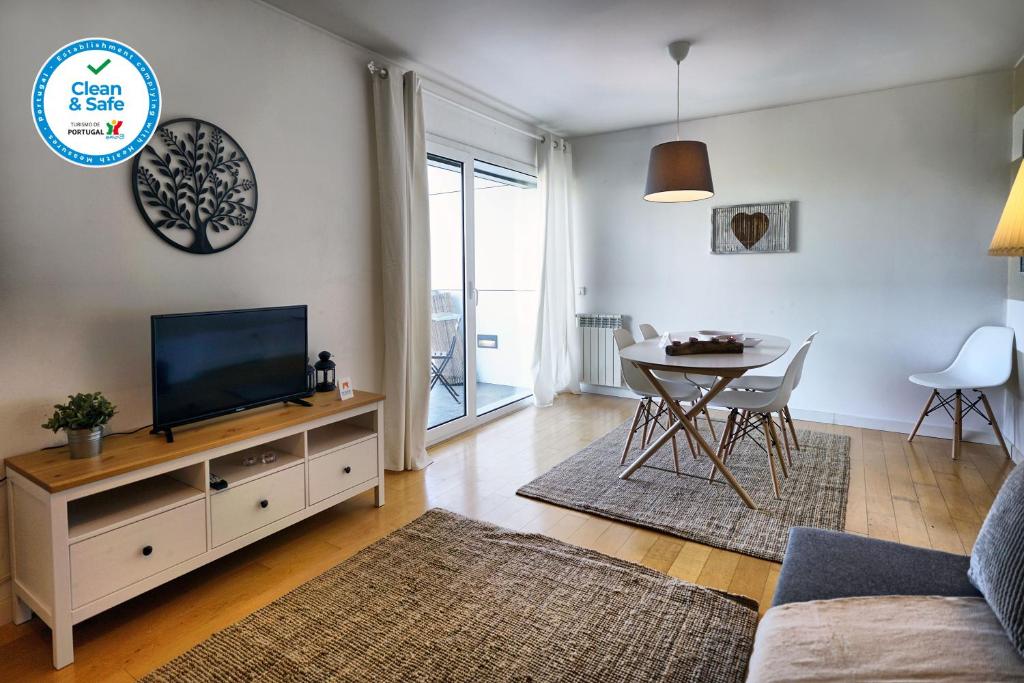 een woonkamer met een televisie en een eettafel bij Bridge View With Balcony in Sacavém