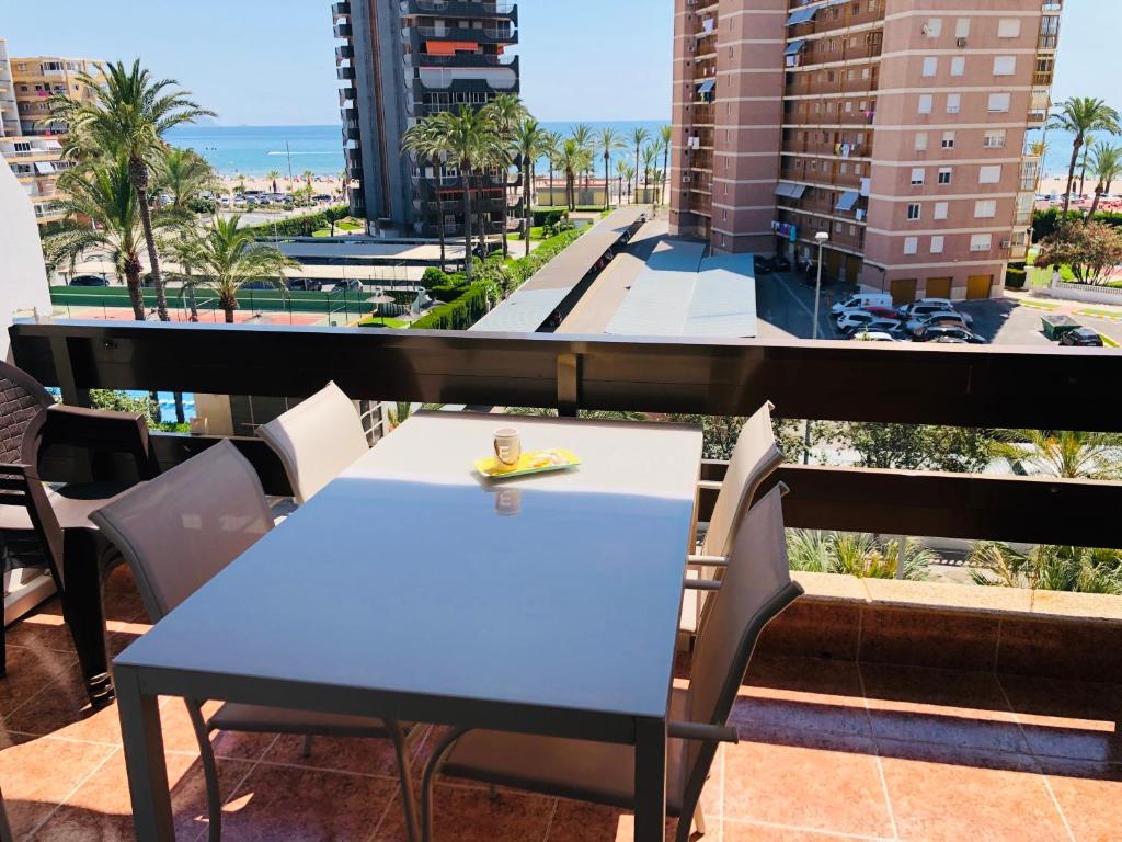 una mesa azul y sillas en un balcón con vistas en Apartamento frente al mar (Avda costa Blanca), en Alicante