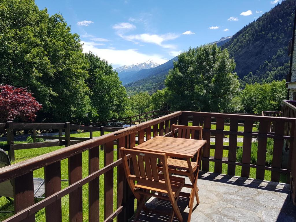 una mesa de madera y una silla en un balcón con montañas en Mont Blanc Apartment Morgex - CIR Alloggio ad uso turistico VDA MORGEX 0008, en Morgex