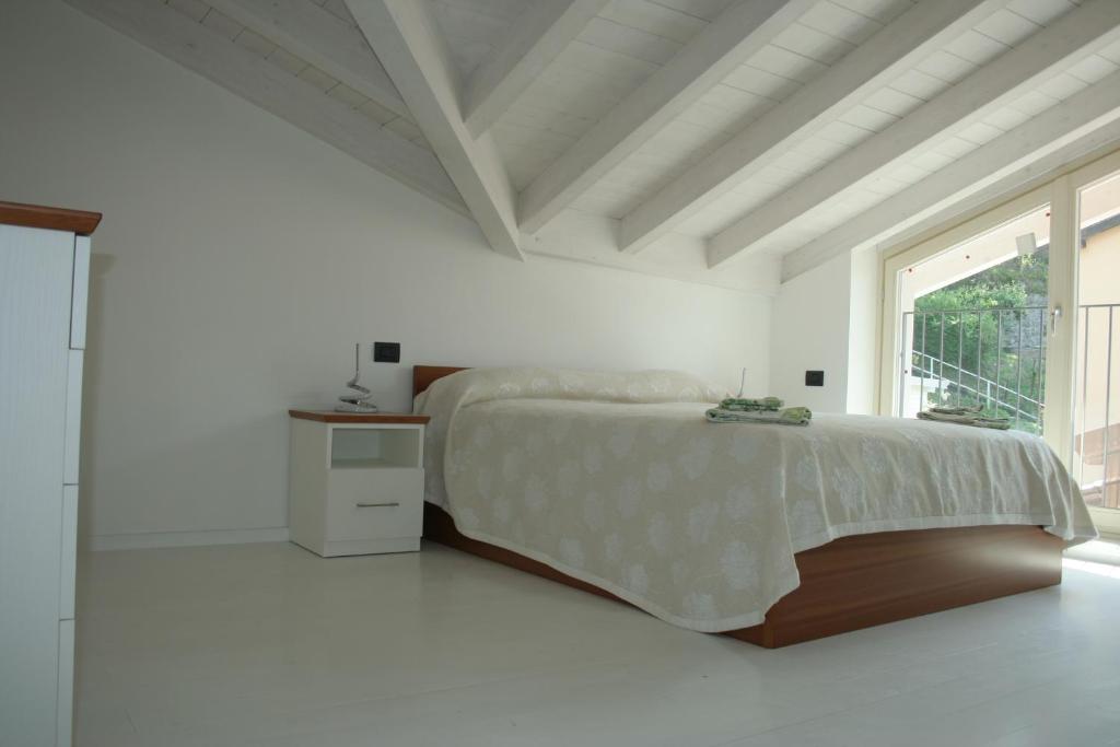 um quarto branco com uma cama e uma janela em appartamenti i fiori del lago em Laveno