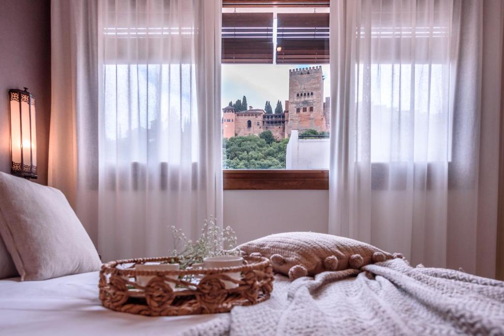 1 dormitorio con 1 cama y una ventana con un castillo en CANDIL SUITE Origen, en Granada