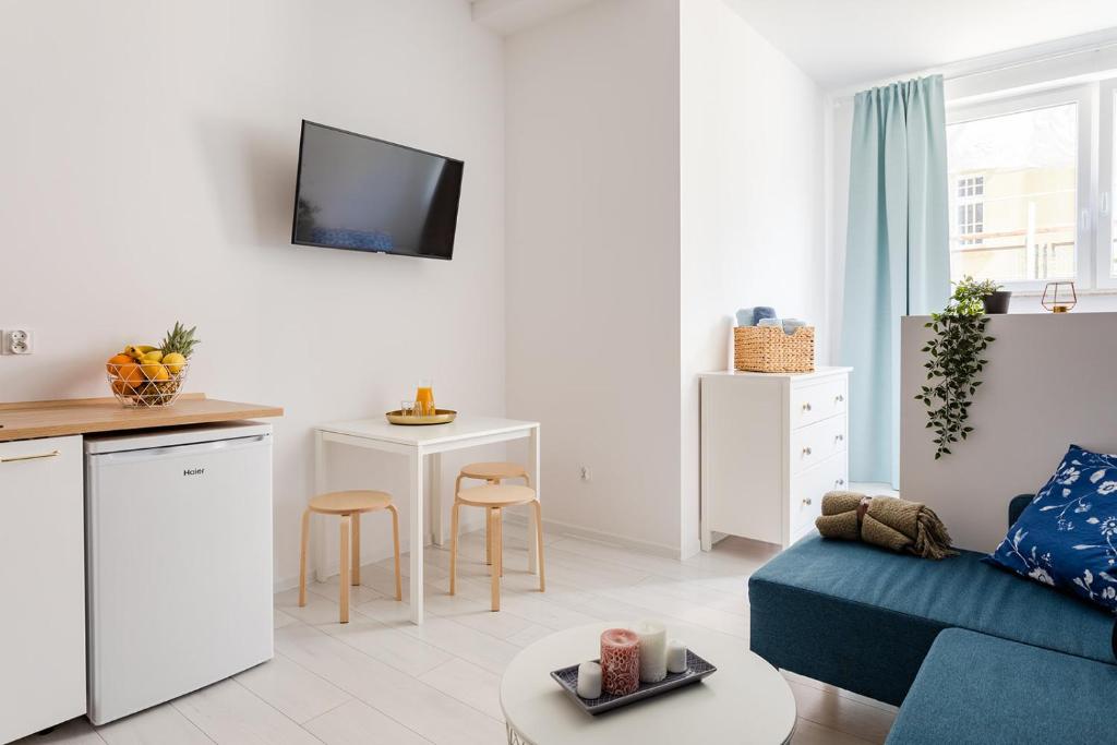 a living room with a blue couch and a kitchen at Open Lakes Apartamenty Giżycko in Giżycko