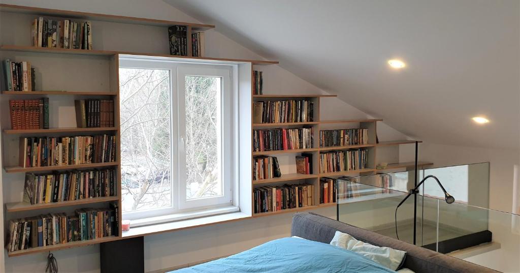 um quarto com uma janela e estantes cheias de livros em Cattleya's Loft em Veliko Tŭrnovo