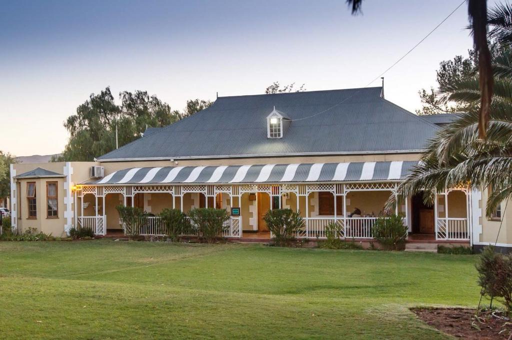 a large white house with a black roof at De Denne Country Guest House in Oudtshoorn