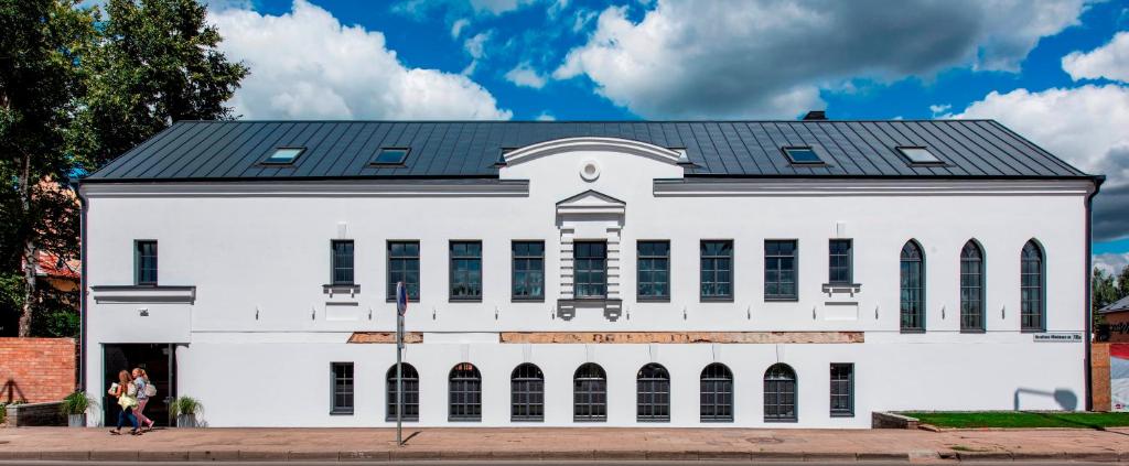 a white building with a black roof at Small attic rooms in Kaunas old town in Kaunas
