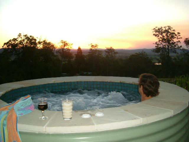 uma pessoa numa banheira de hidromassagem com um copo de vinho em Wallaby Ridge Retreat em Mount Tamborine