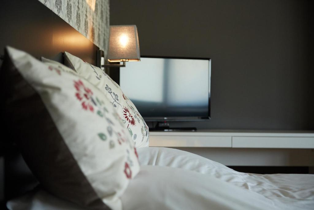 um quarto com uma cama, uma televisão e almofadas em Focus Boutique em Kortrijk