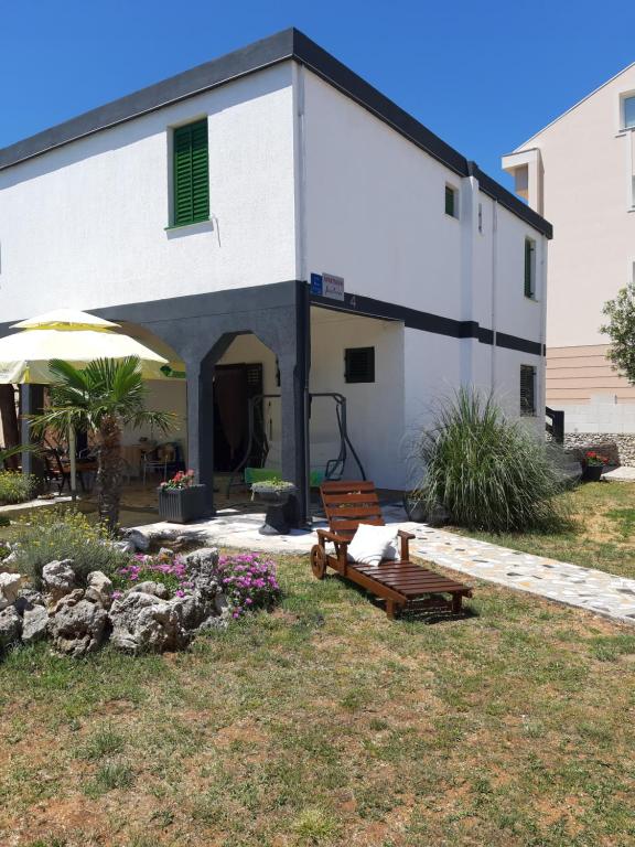 a white building with a bench in front of it at Apartmani Jadra in Stara Novalja
