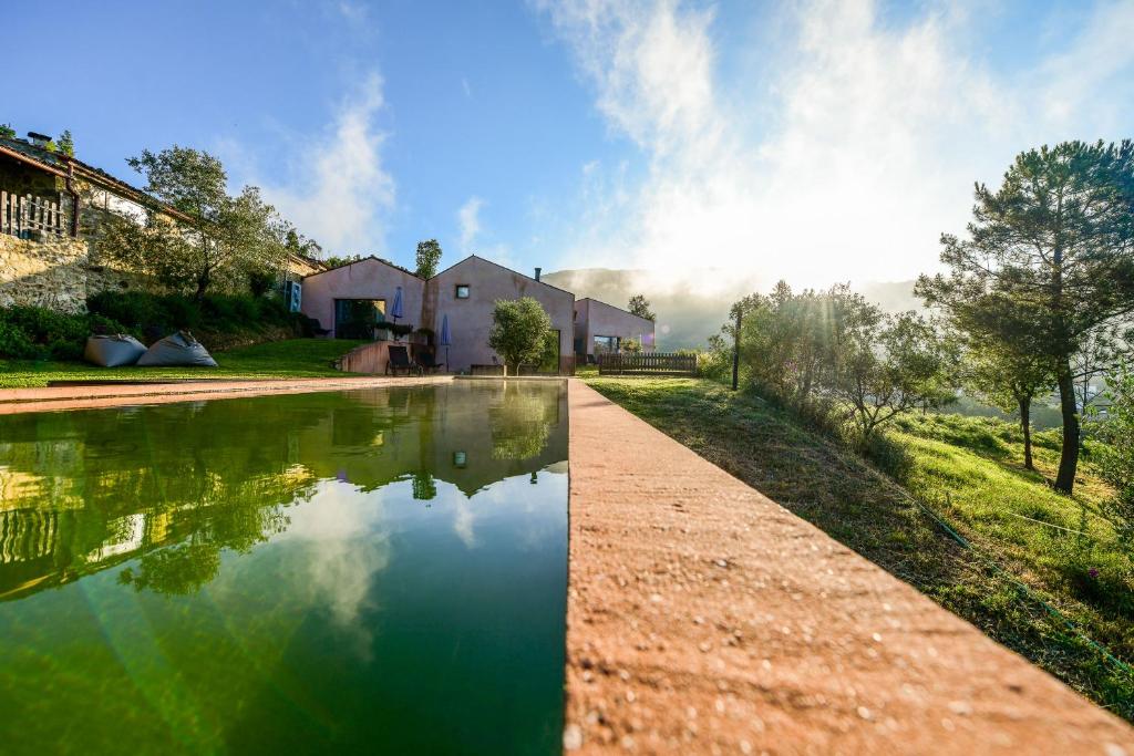 un cuerpo de agua junto a una casa en Vale do Ninho Nature Houses, en Ferraria de São João