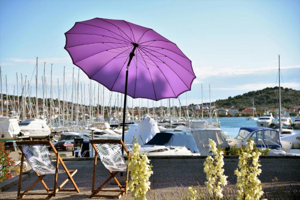 un paraguas púrpura sentado frente a un puerto deportivo en HOUSE IVY en Murter