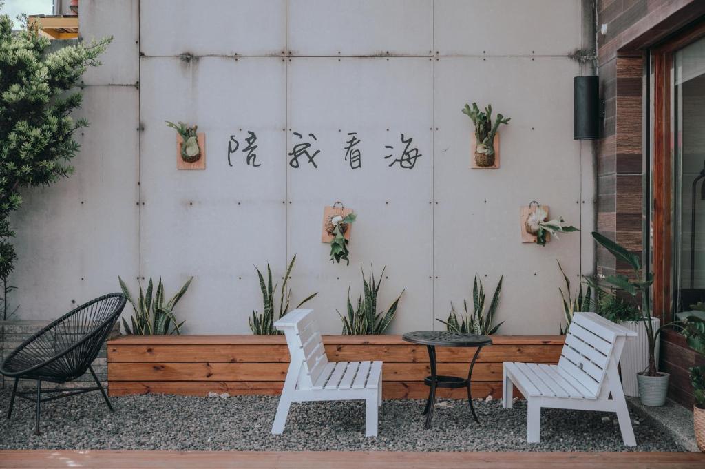 two white chairs and a table in front of a wall at Sasa Nor Lamour B&B in Eluan