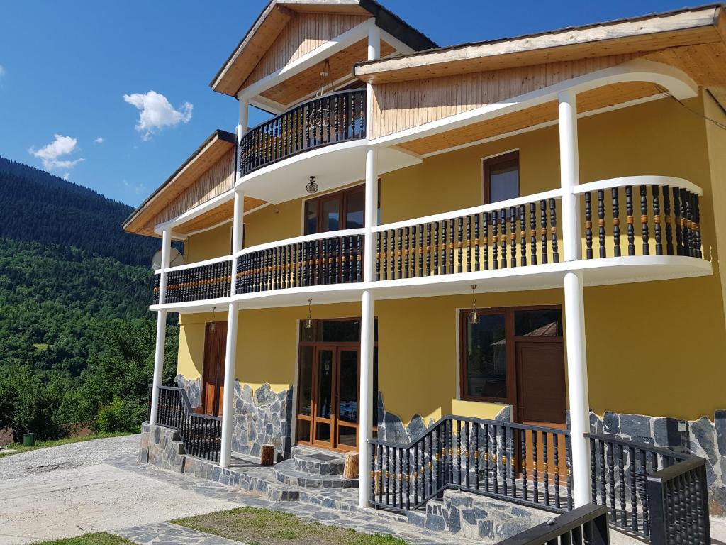 Cette grande maison jaune possède un balcon. dans l'établissement Hilltop Mestia, à Mestia