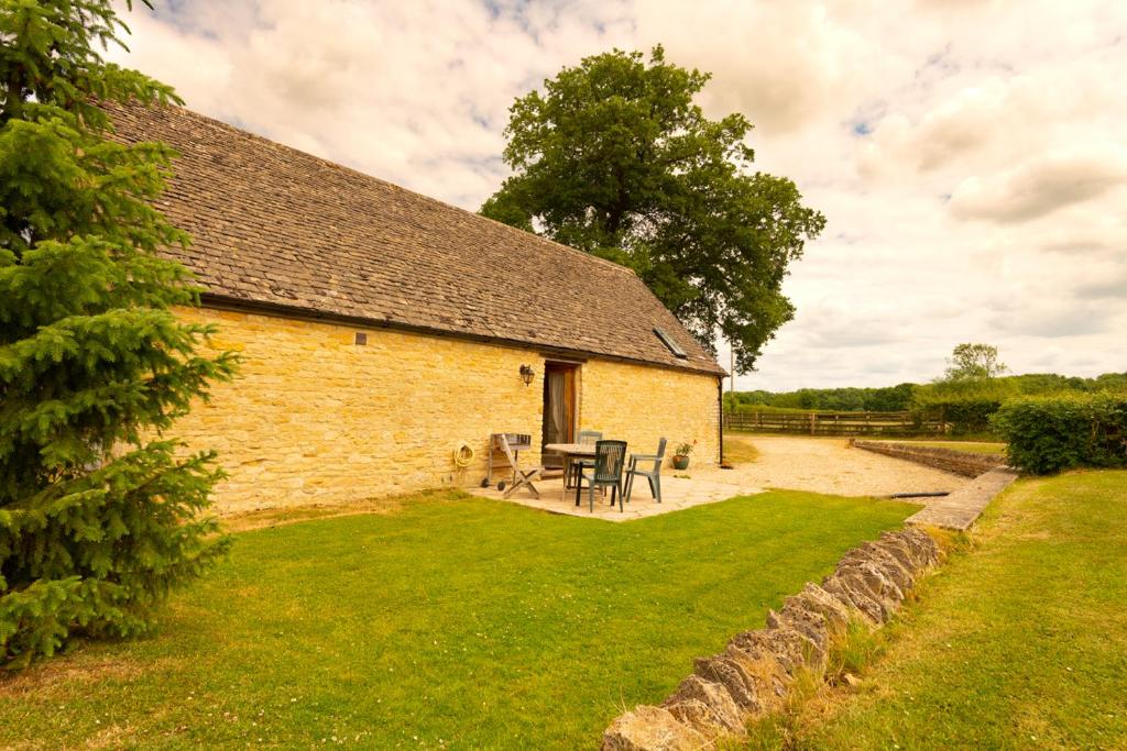 un antiguo edificio de piedra con una mesa de picnic delante de él en The Oaks - Ash Farm Cotswolds, en Stow on the Wold