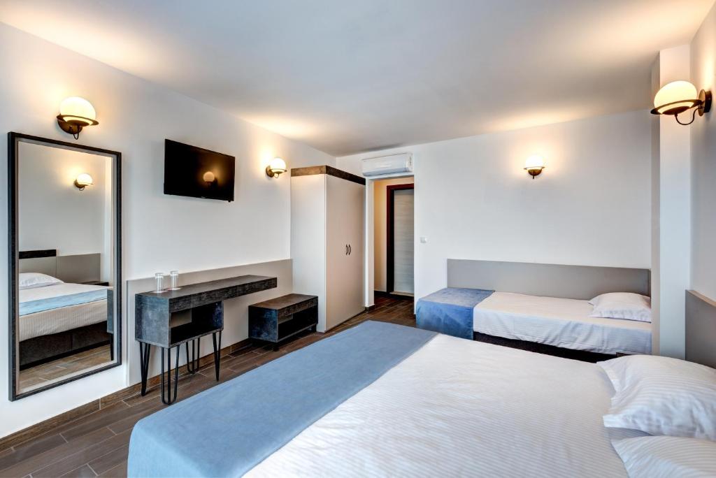 ネセバルにあるPanorama Blue Family Hotel and Free parkingのベッドが2つと鏡があるホテルの部屋