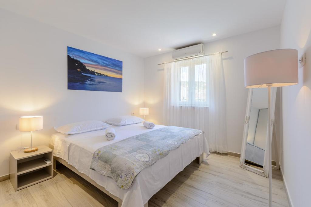 a white bedroom with a bed and a television at CITY VIEW APARTMENT in Sutivan