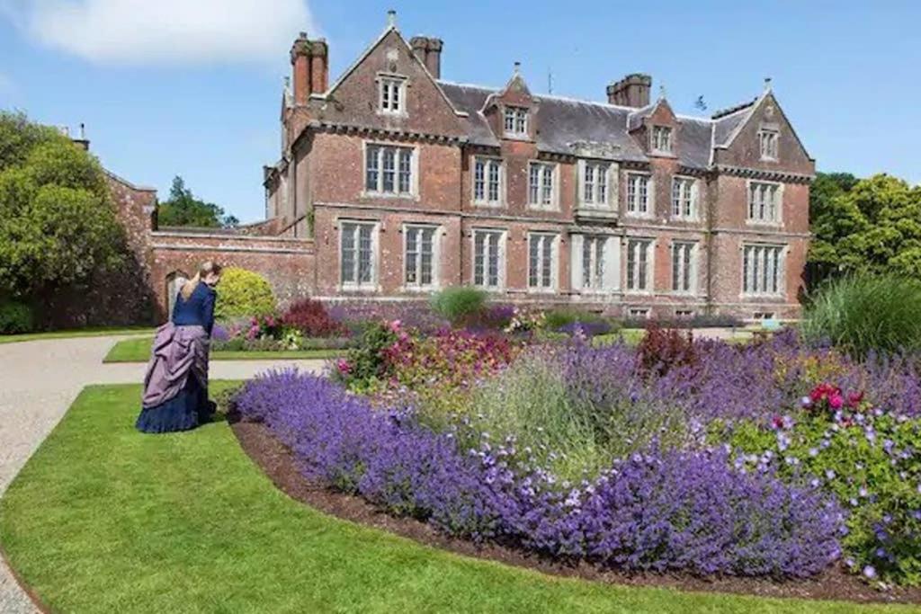 a woman standing in a garden in front of a castle at The Gardeners Cottage at Wells House in Glenranny