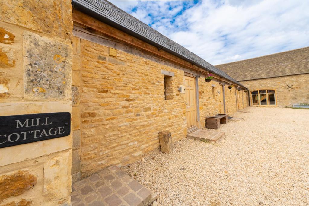 a brick building with a sign that reads mill cottage at Mill Cottage 2 - Ash Farm Cotswolds in Stow on the Wold