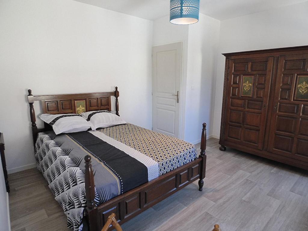 a bedroom with a bed and a wooden cabinet at Le Coustalou in Puybrun