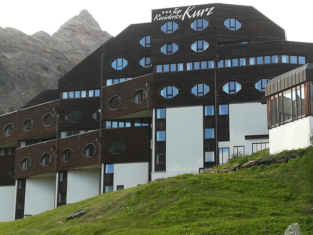 un edificio in cima a una collina con montagne sullo sfondo di Residence kurtz a Maso Corto