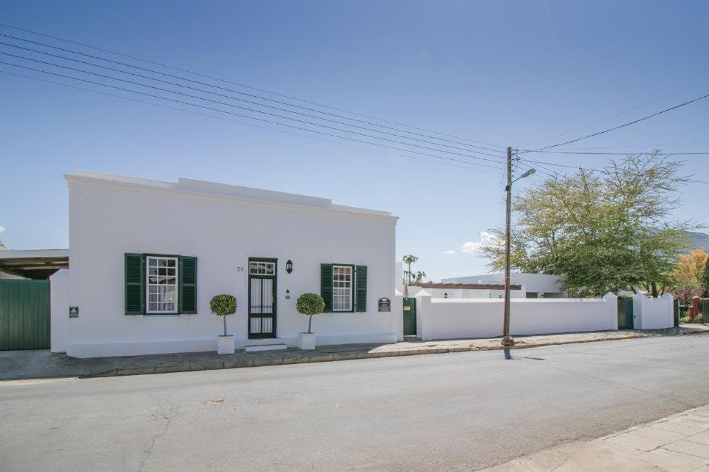 un edificio blanco con persianas verdes en una calle en 54 on Middle - Solar-powered stay, en Graaff-Reinet