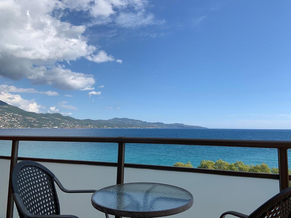 a balcony with a table and chairs and the ocean at Hotel Flisvos in Kalamata
