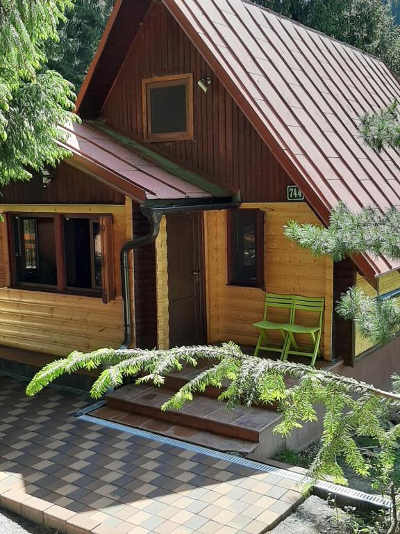 a wooden house with a green chair in front of it at Chata Safran in Donovaly
