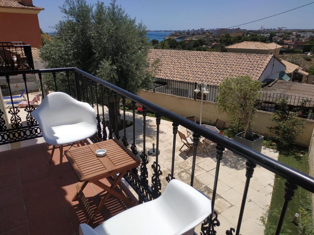 Un balcón con 2 sillas blancas y una mesa. en Apartamento vistas al mar - Coveta Fuma, en El Campello