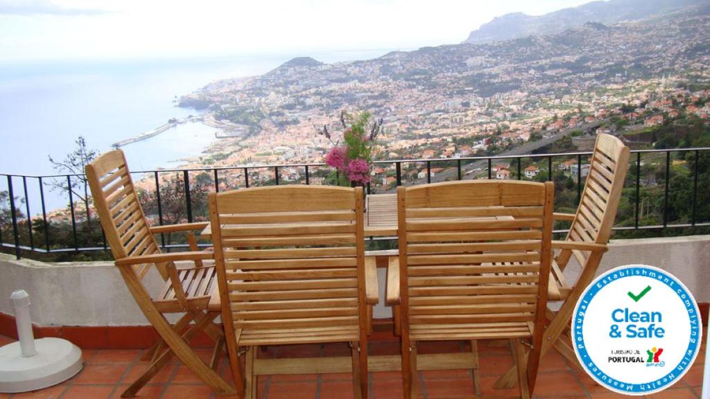 een tafel en stoelen met uitzicht op de oceaan bij Apartamento Charmoso no Funchal, com grande Jardim e Vista Esplêndida in Funchal