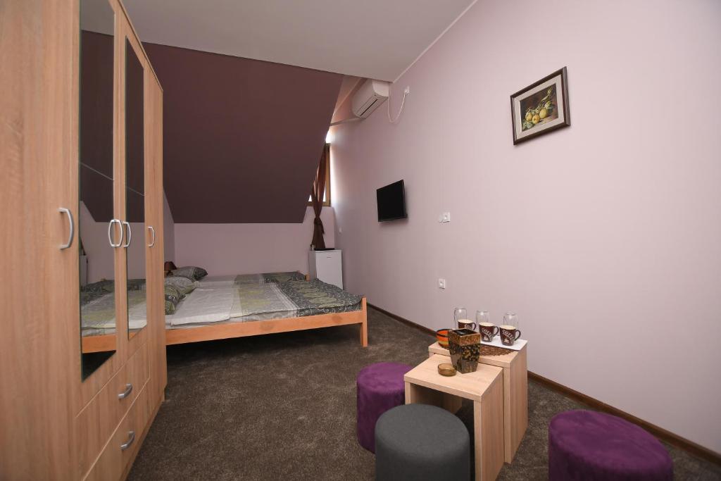 a bedroom with a bed and a table with purple chairs at Apartmani Genčić 3 in Kladovo
