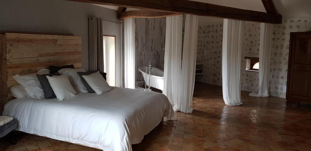 a bedroom with a white bed and a bath tub at La Maison Josnes de Mady in Josnes
