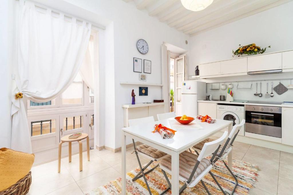 a white kitchen with a white table and chairs at Alojamientos Cadiz Sol in Cádiz