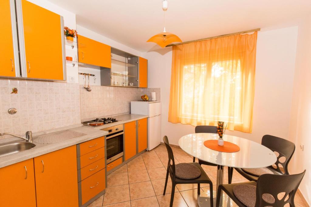 une cuisine avec des armoires orange, une table et des chaises dans l'établissement Apartman Magi, à Zadar