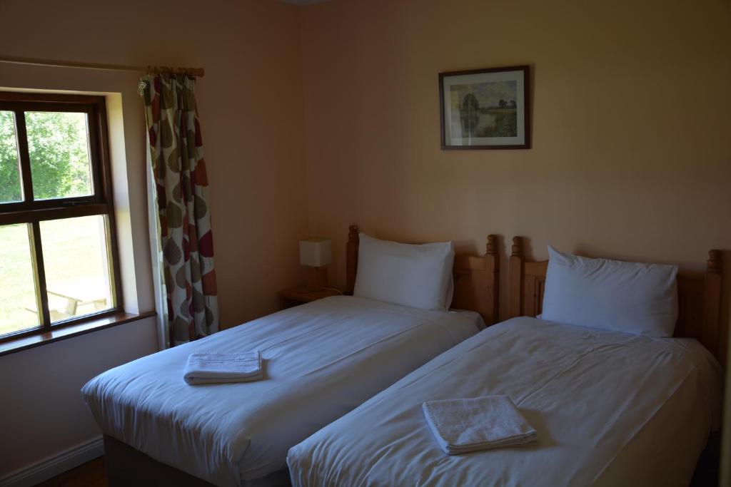 two twin beds in a room with a window at Amber Cottage in Killarney